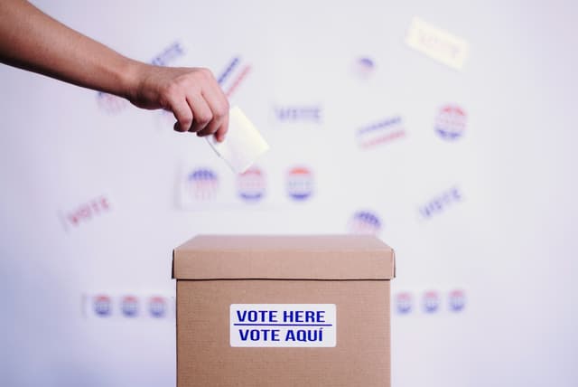 Ballot box that says vote here on it. 