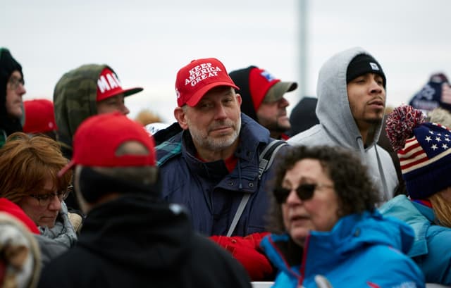 Person standing in a crowd wearing a make america great hat. 