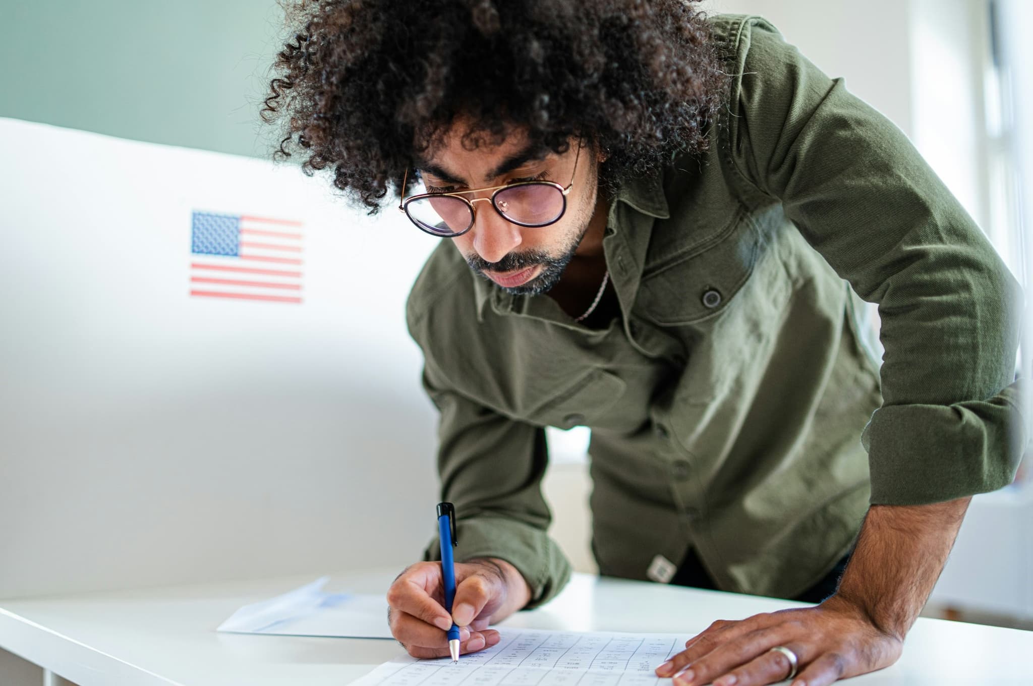 Voter with glasses filling out their ballot. 